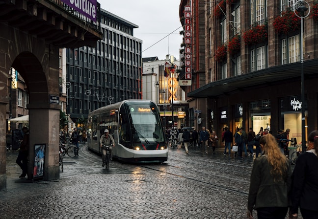 people walking on sidewalk near white and black tram during night time