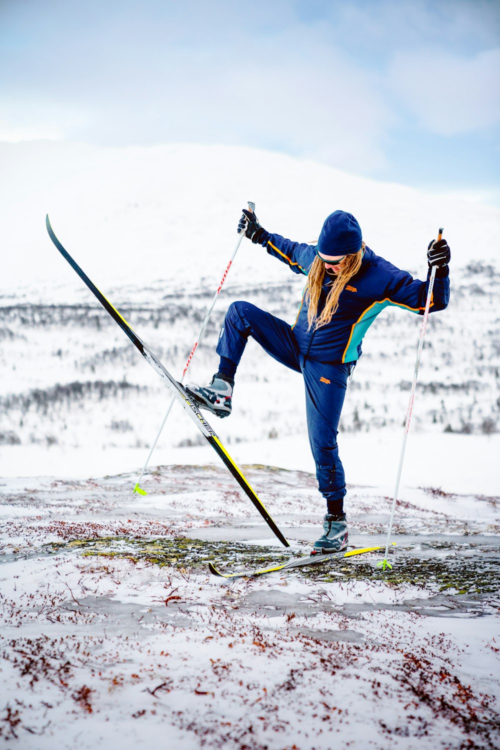 hombre en chaqueta azul y pantalones azules montando en hojas de esquí en suelo cubierto de nieve durante