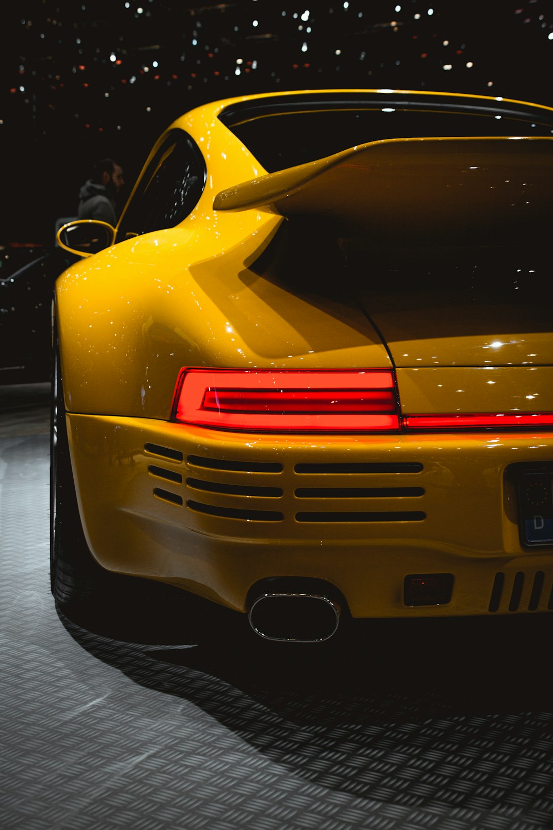 yellow porsche 911 parked beside black car