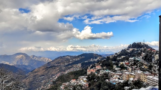 aerial view of city near mountains under cloudy sky during daytime in Shimla India
