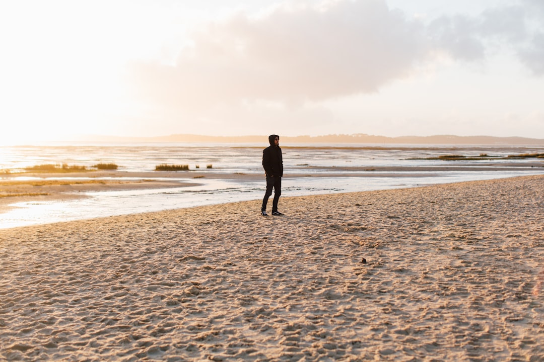 man in black jacket walking on beach during daytime