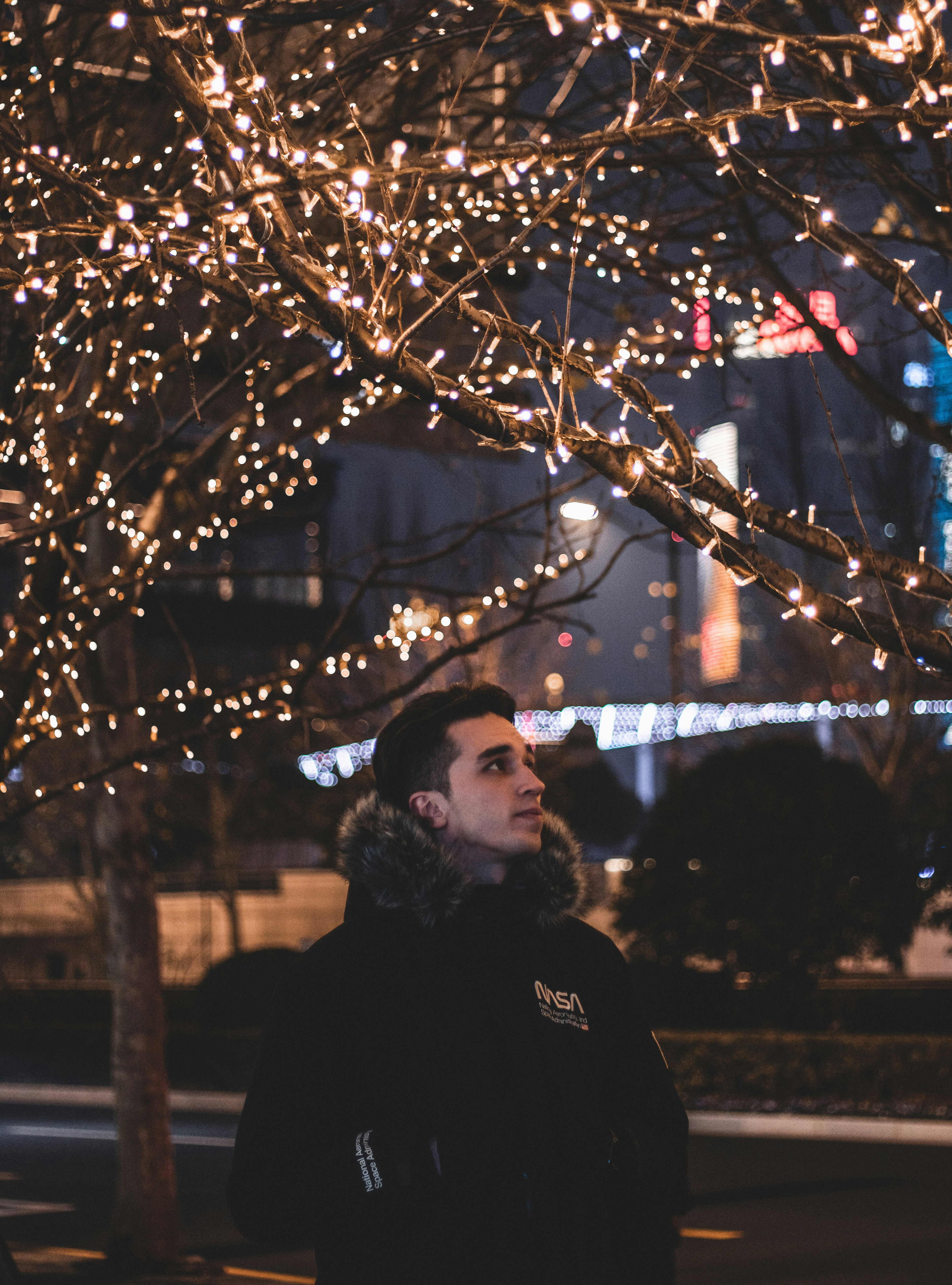 woman in black hoodie standing near brown tree during daytime