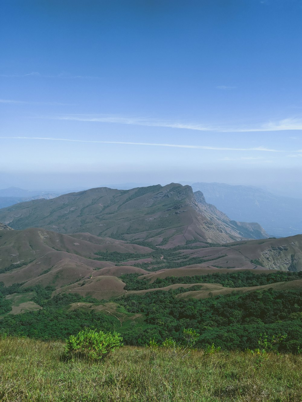 green grass field and mountains under blue sky during daytime