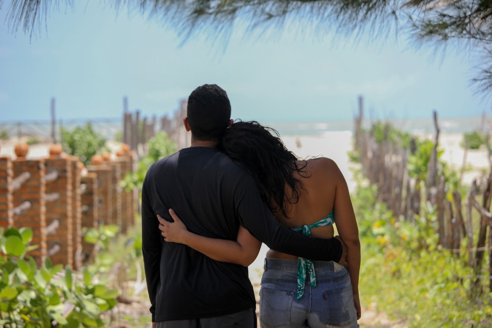 man in black shirt kissing woman in white shirt during daytime