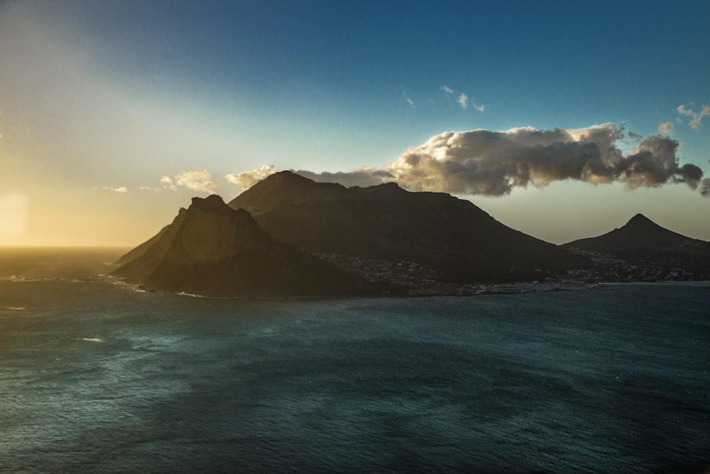 green mountain beside blue sea under blue sky during daytime