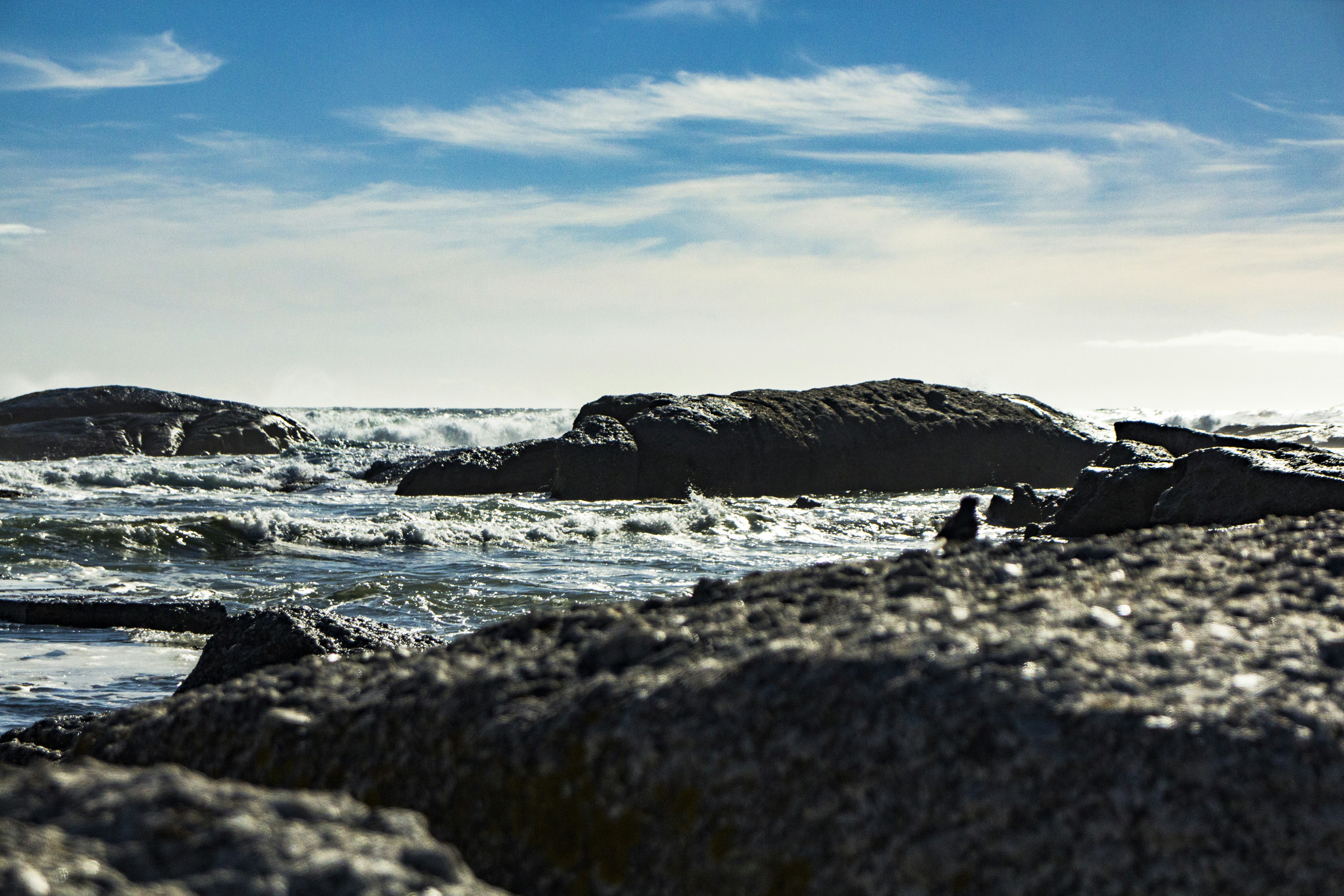 brown rock formation on sea under blue sky during daytime