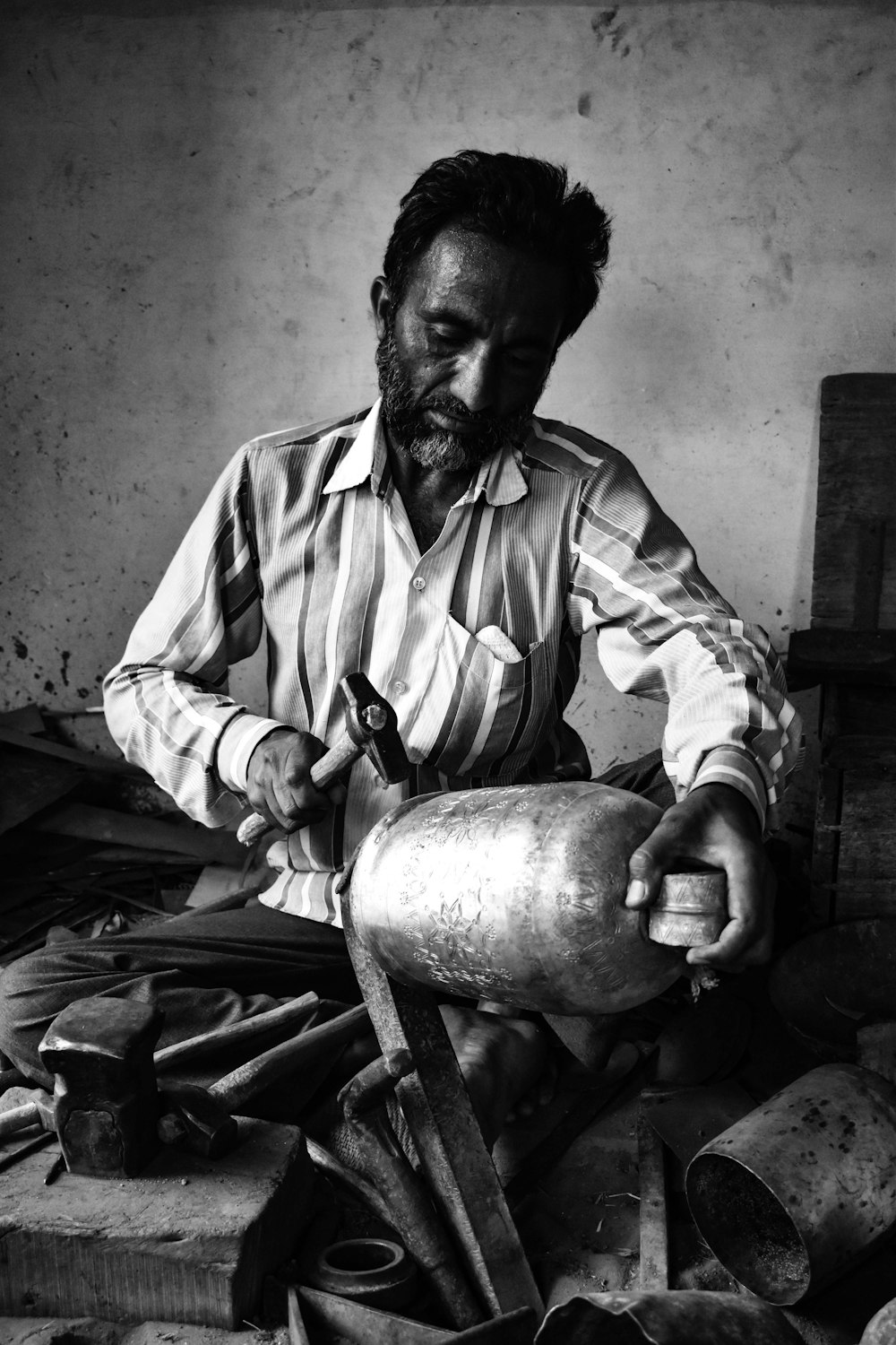 a black and white photo of a man working on a metal object