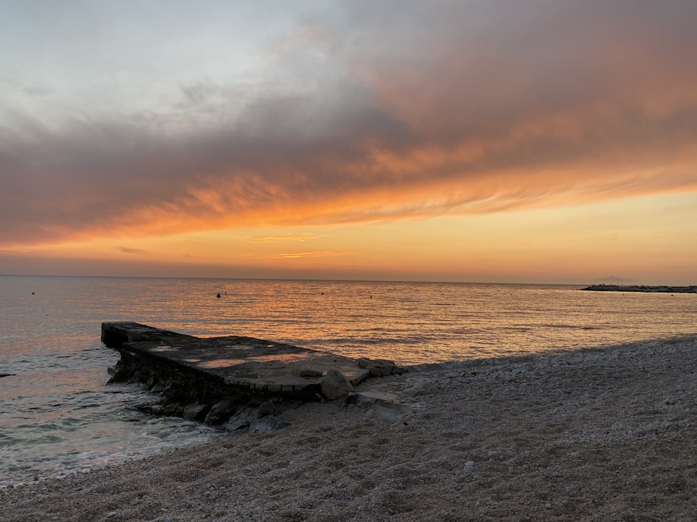 Formazione rocciosa marrone sulla riva del mare durante il tramonto