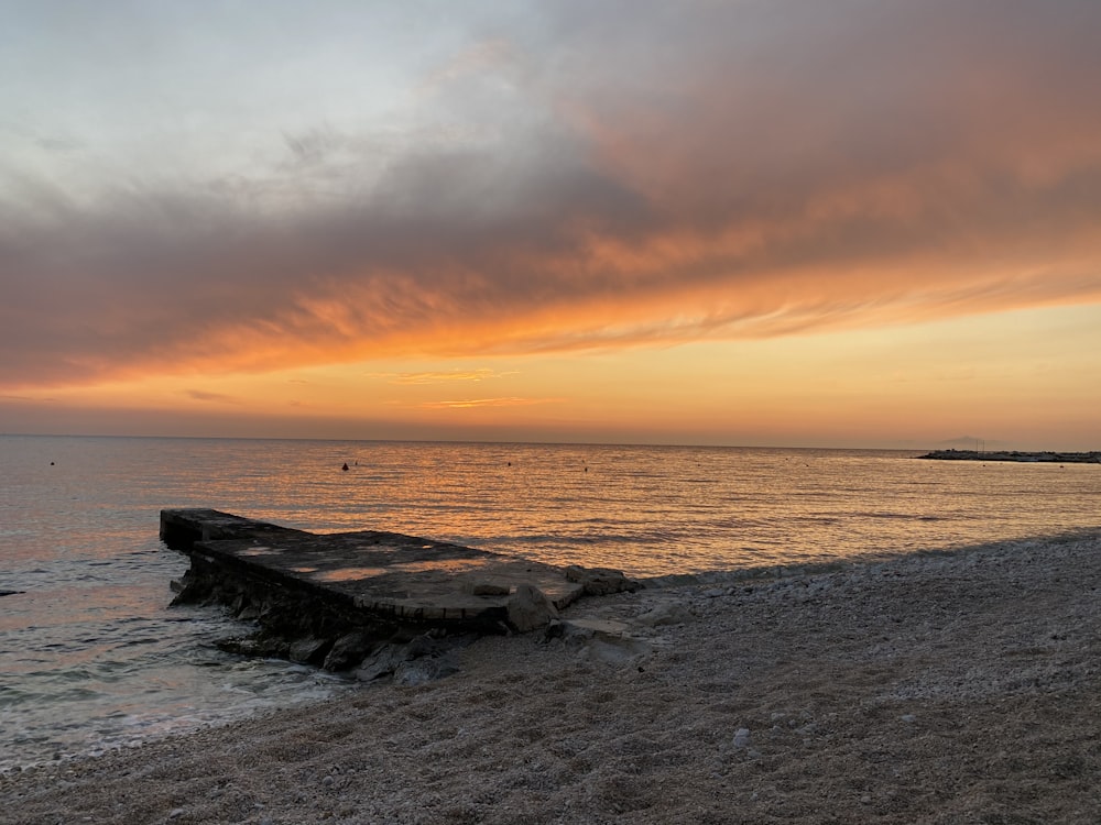 formação rochosa marrom na costa do mar durante o pôr do sol