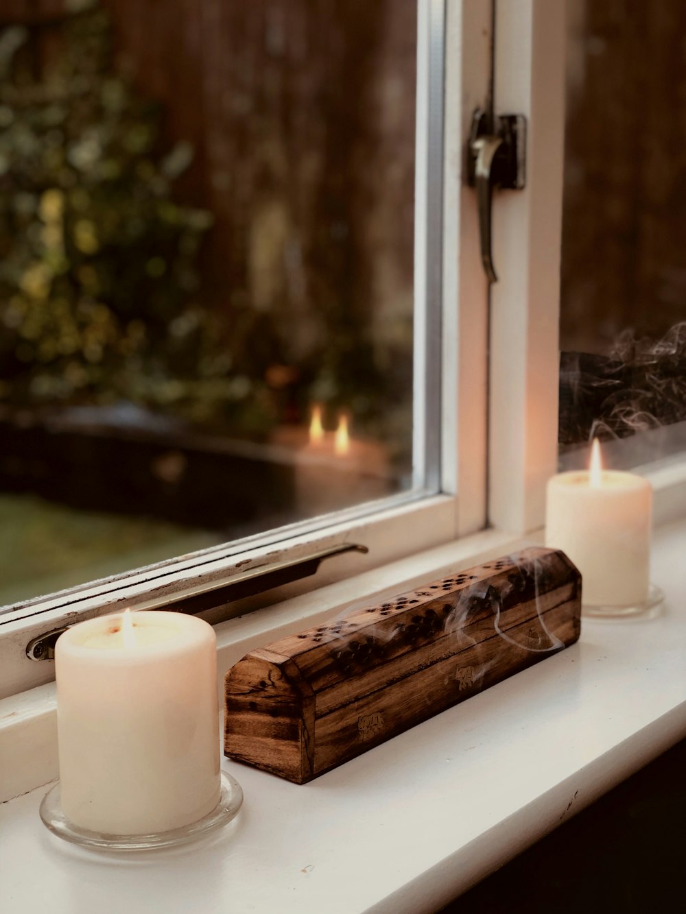 white pillar candle beside window