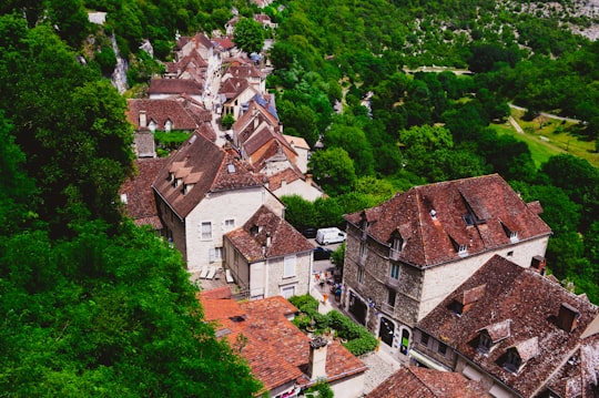 brown and white concrete houses surrounded by green trees during daytime in Causses du Quercy Natural Regional Park France