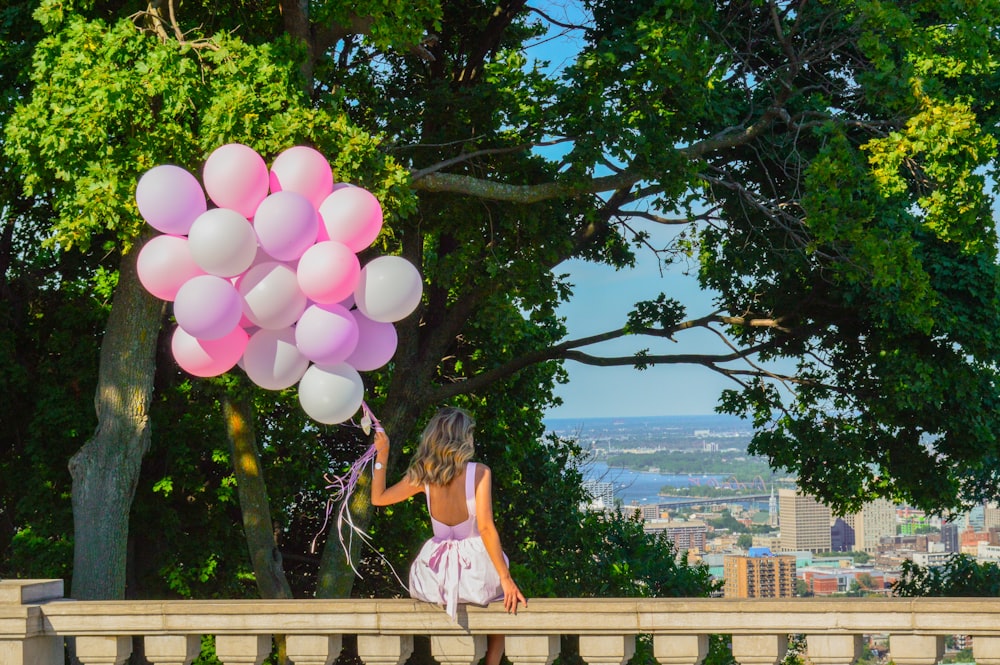 menina na regata cor-de-rosa e shorts cor-de-rosa segurando balões