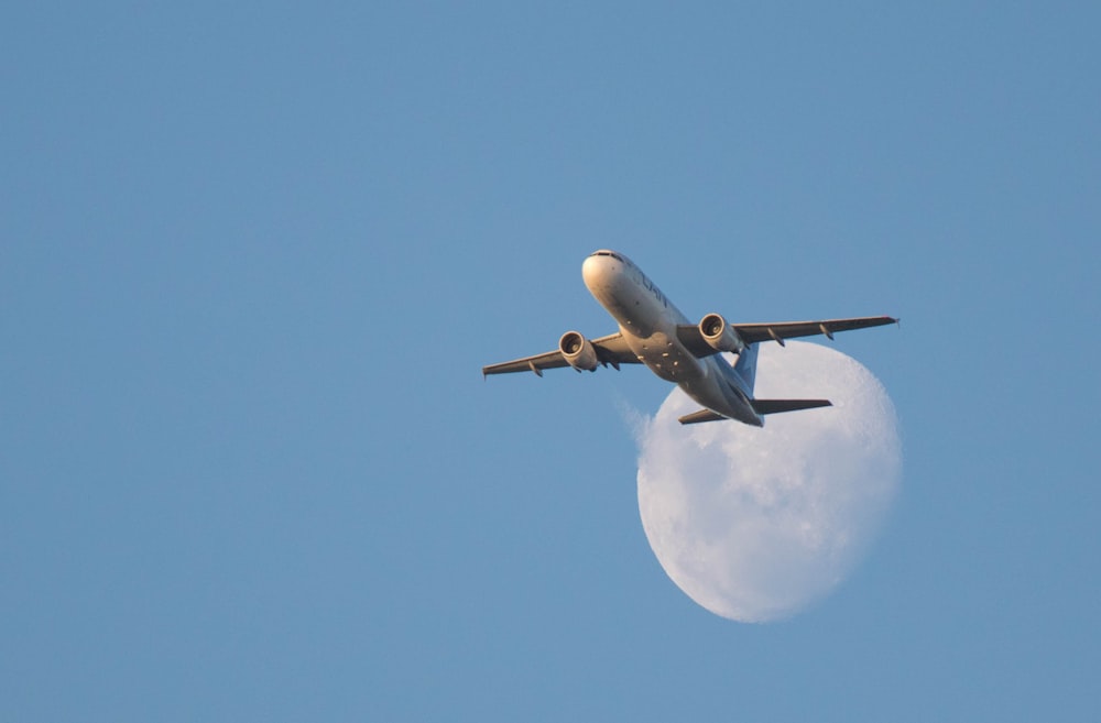 white airplane in mid air during daytime