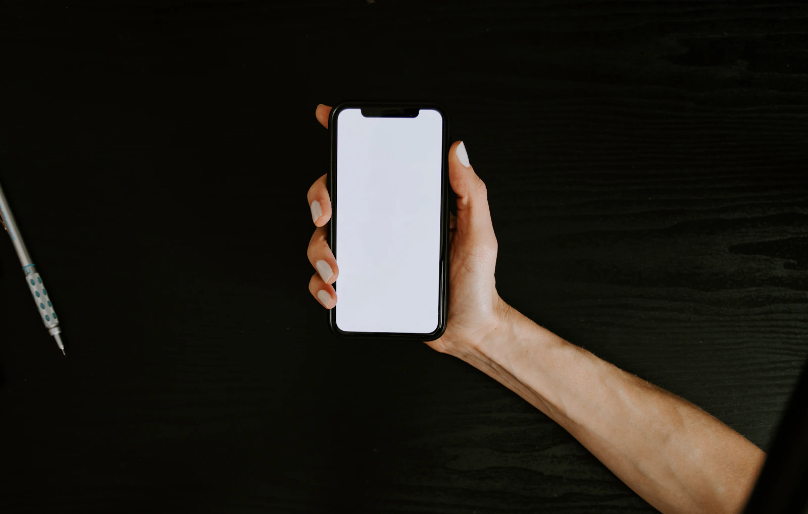 A hand holding a smartphone against a dark background