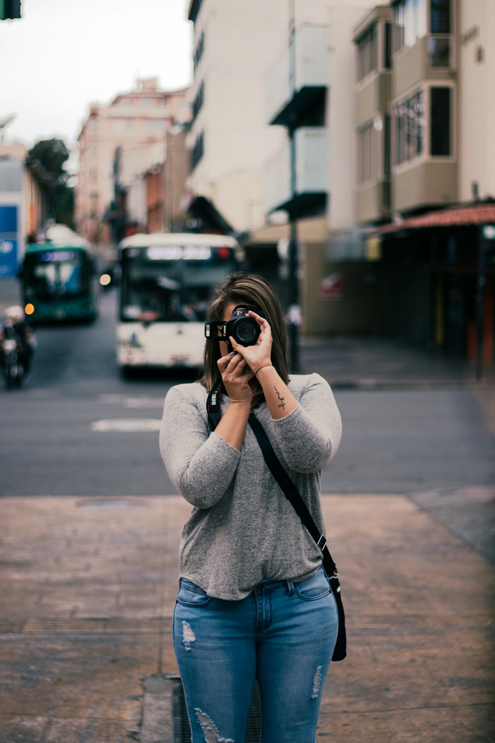 woman in gray sweater taking photo using black dslr camera