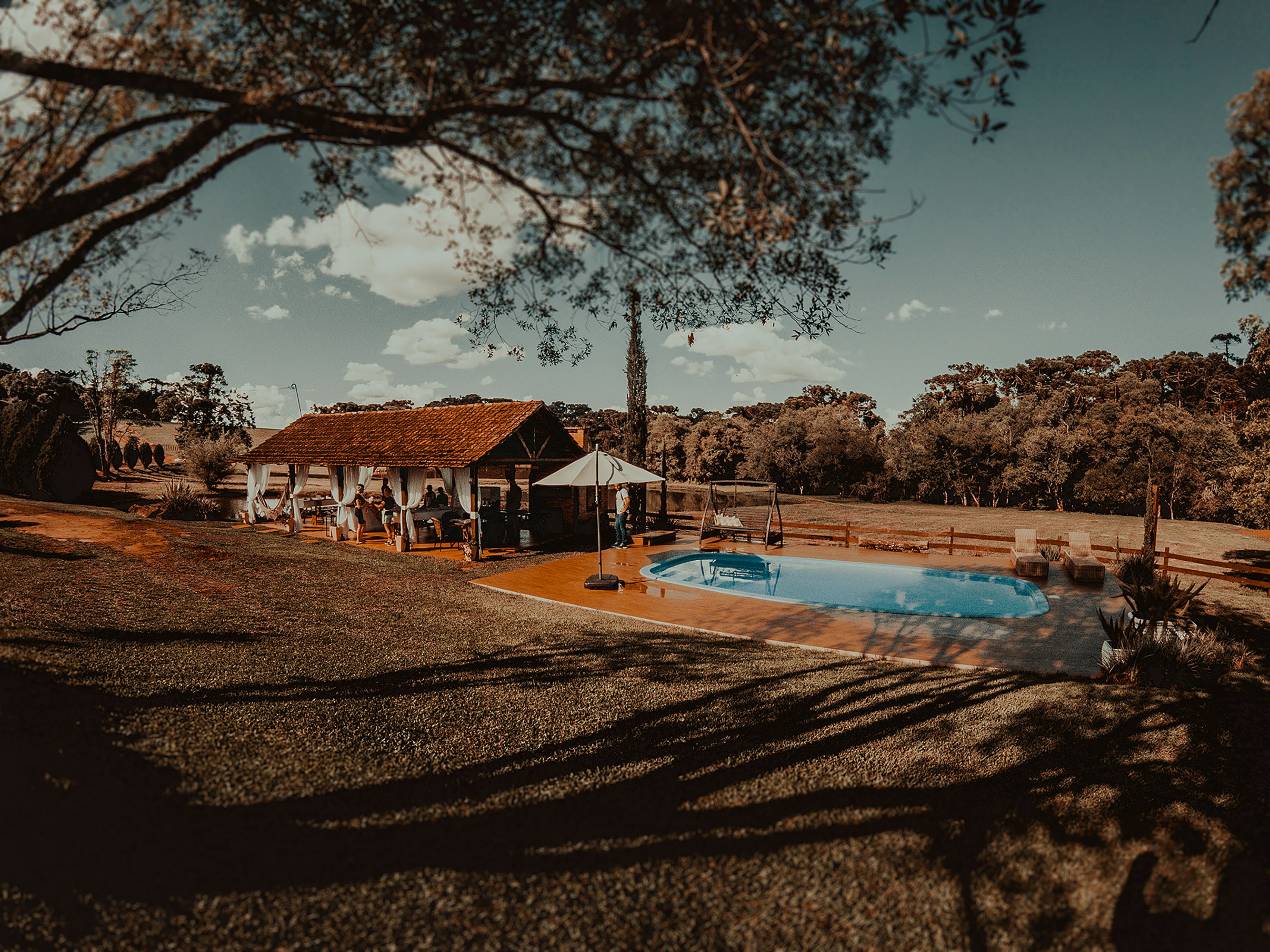 brown wooden house near trees and swimming pool under blue sky during daytime