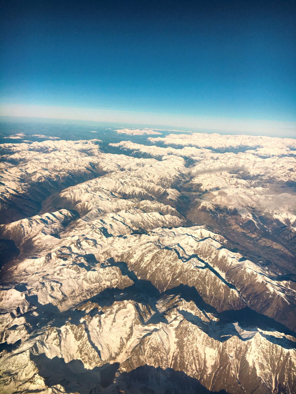 昼間の青空の下での白と灰色の山々の航空写真