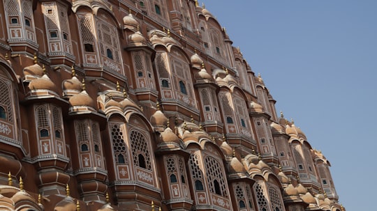 brown concrete building under blue sky during daytime in Hawa Mahal India