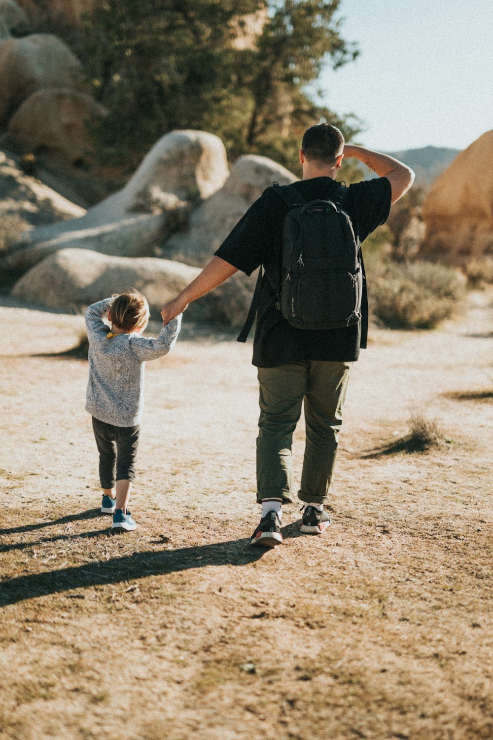 man in black t-shirt holding child in gray hoodie