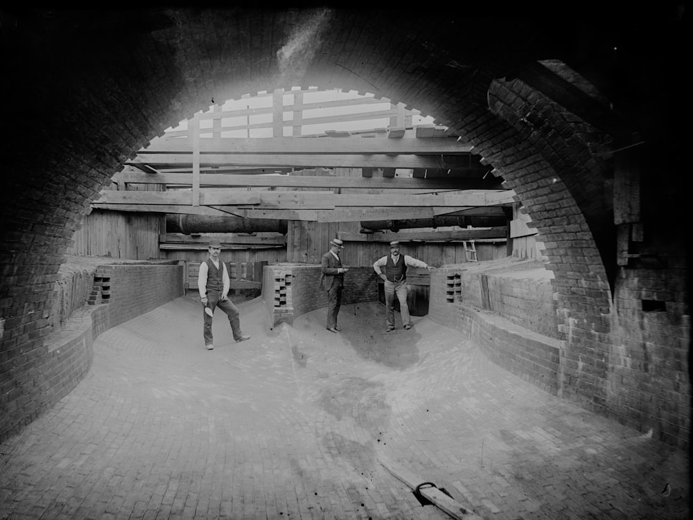 grayscale photo of 2 men walking on tunnel