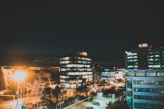 Nighttime cityscape featuring office buildings lit by the company’s energy-efficient commercial lights.