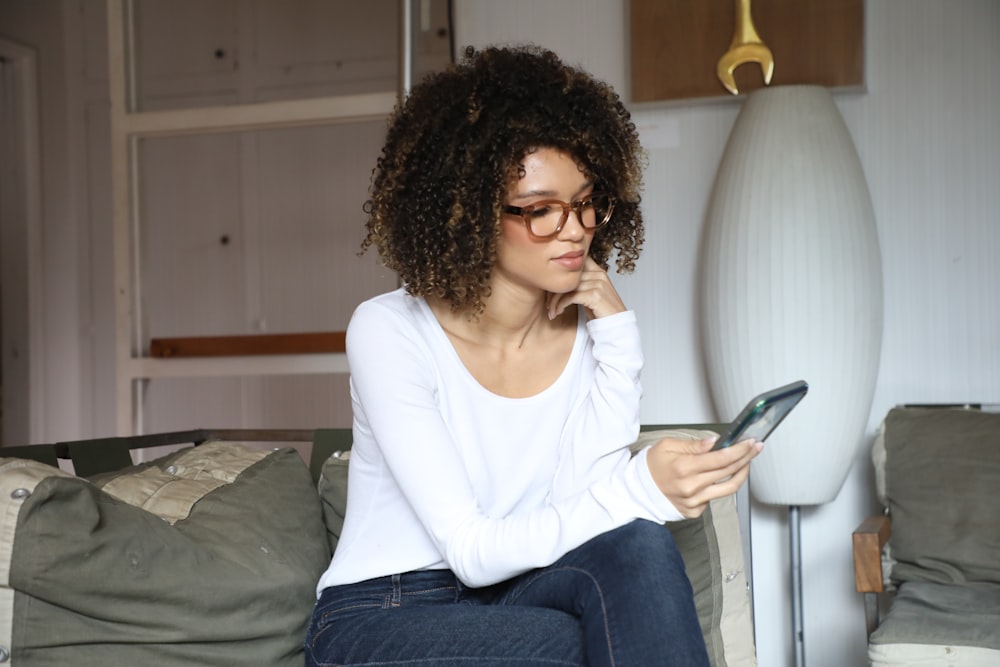 woman in white long sleeve shirt and blue denim jeans sitting on bed