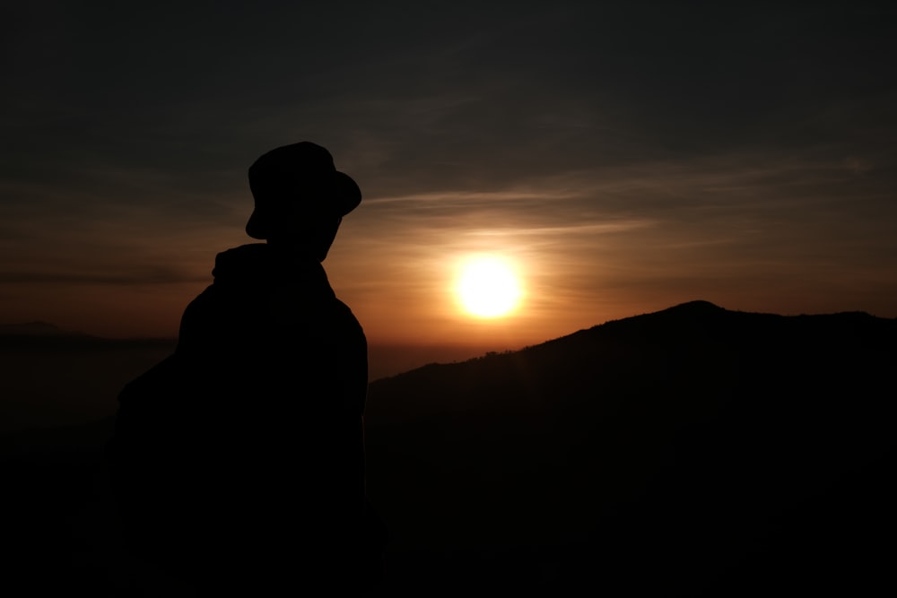 夕暮れ時の山に立つ男のシルエット