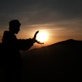 silhouette of man standing on top of mountain during sunset