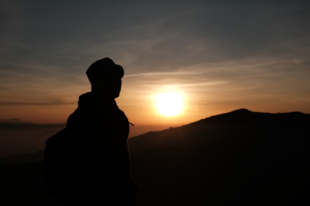 夕暮れ時の山に立つ男のシルエット