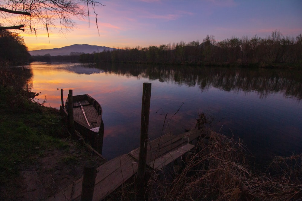 Muelle de madera marrón en el lago durante la puesta del sol