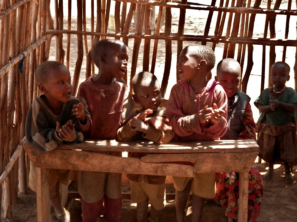 children sitting on brown wooden bench