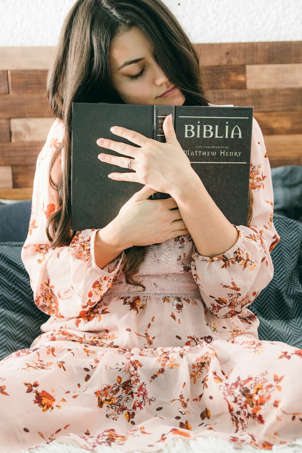 Femme en robe fleurie blanche et rouge tenant un livre noir