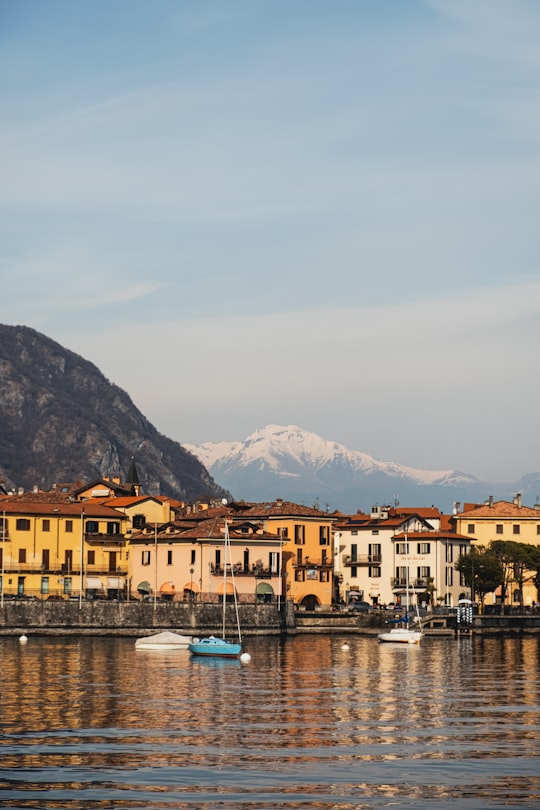 yellow and white concrete building near body of water during daytime in Como Italy