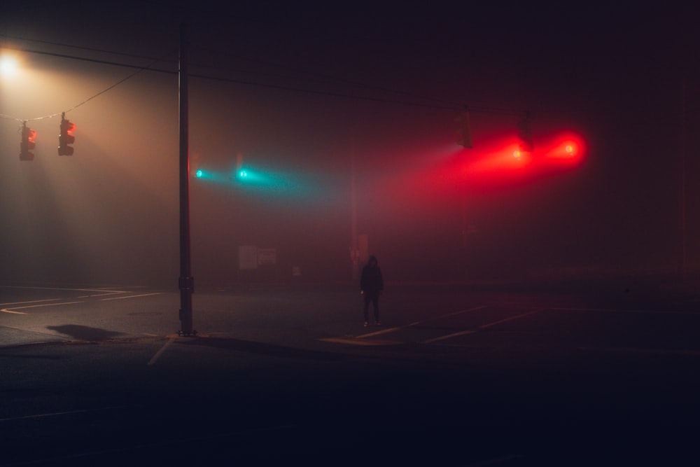 man in black jacket standing on sidewalk during night time