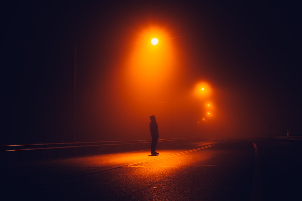 silhouette of person walking on road during sunset