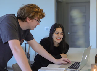 man and woman sitting at table using laptop computer