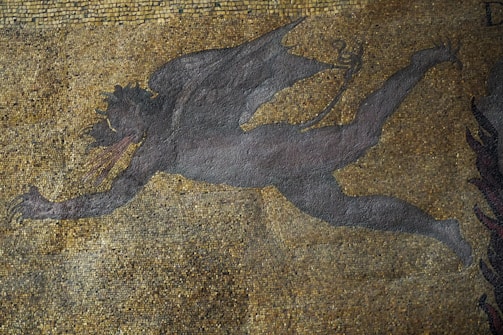 A mosaic artwork featuring a dark, winged figure in motion against a backdrop of small, multicolored tiles. The figure appears to be mythical, with elongated limbs and horns, conveying a sense of dynamic movement.