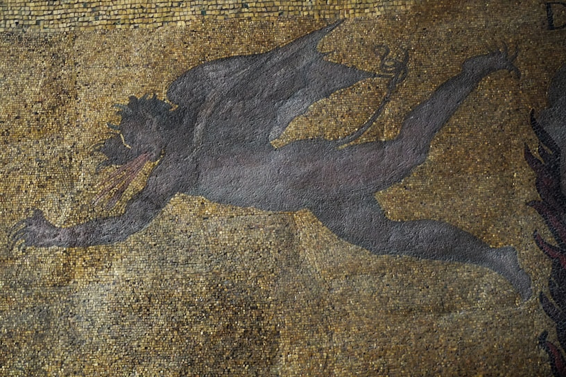A mosaic artwork featuring a dark, winged figure in motion against a backdrop of small, multicolored tiles. The figure appears to be mythical, with elongated limbs and horns, conveying a sense of dynamic movement.
