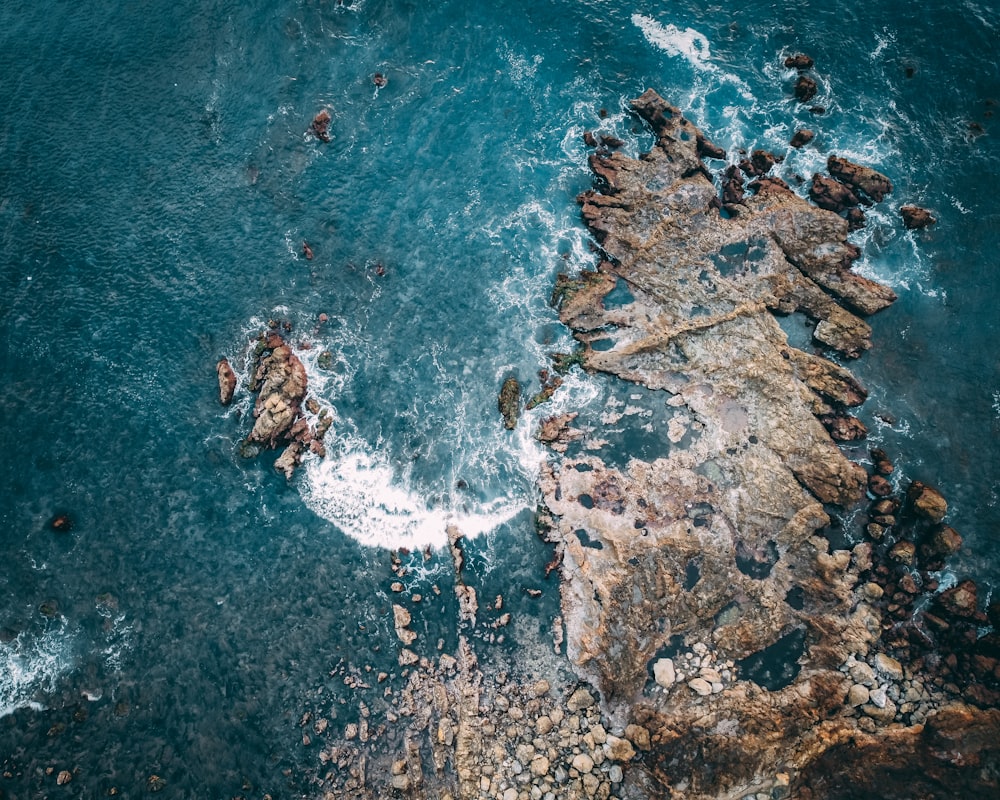 aerial view of ocean waves crashing on rocks during daytime