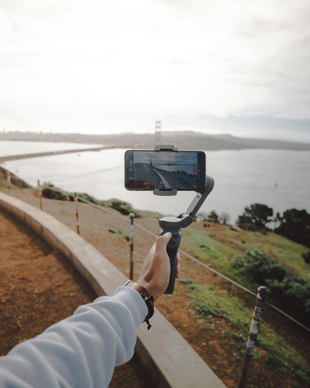 person holding black camera taking photo of bridge during daytime