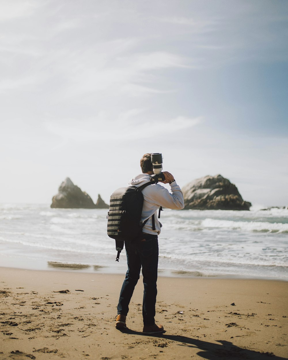 man in black jacket and black pants standing on seashore during daytime