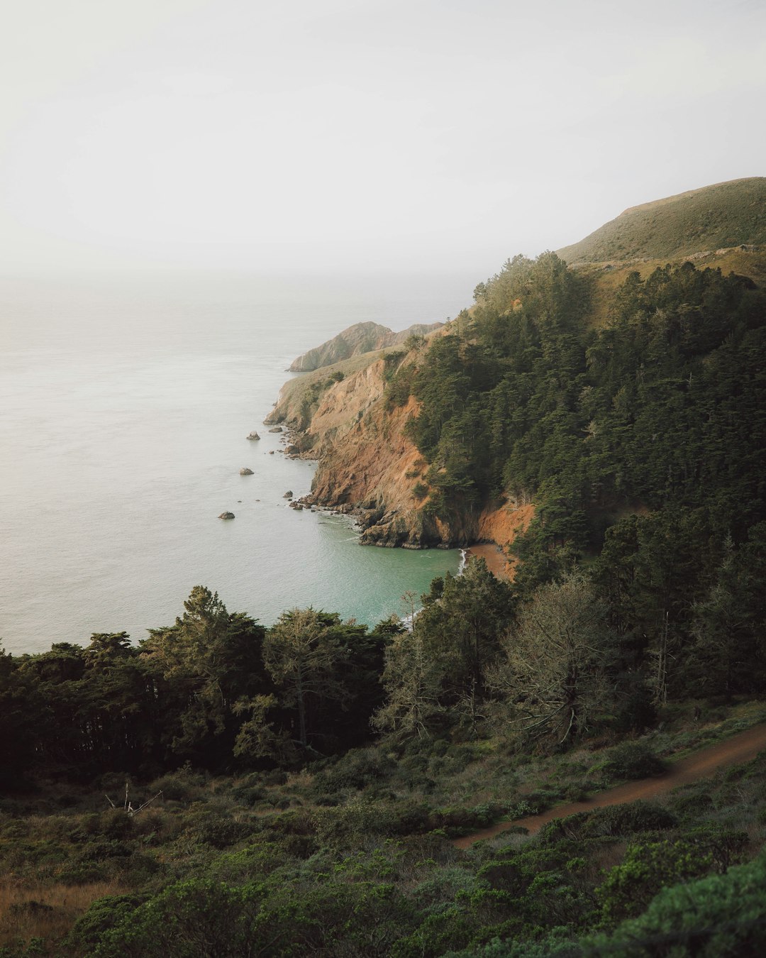 green and brown mountain beside body of water during daytime