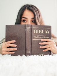 woman covering her face with book