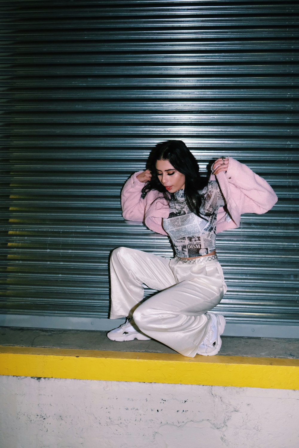 woman in pink hoodie and white pants sitting on floor