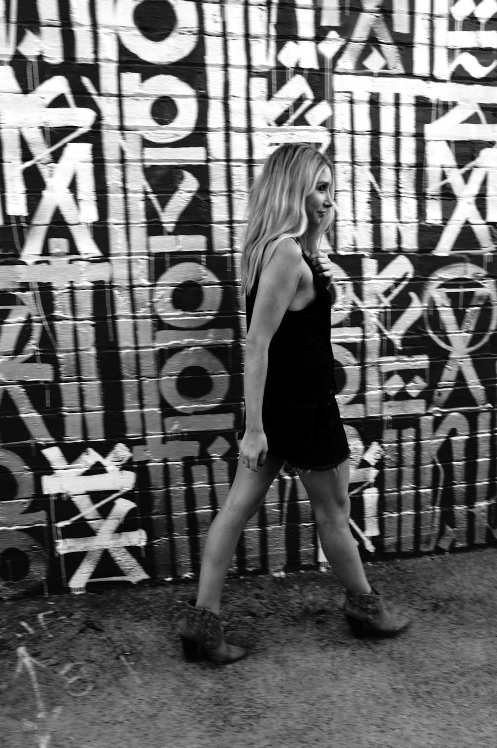 a woman walking past a wall covered in graffiti