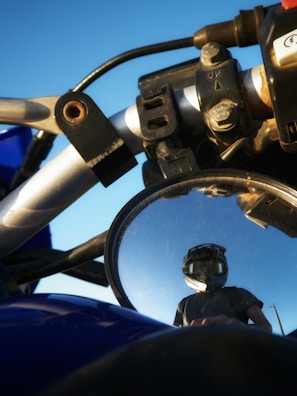 A close-up of motorcycle handlebars with a clear blue sky in the background.