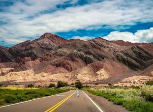 gray asphalt road in between brown mountains under blue sky during daytime