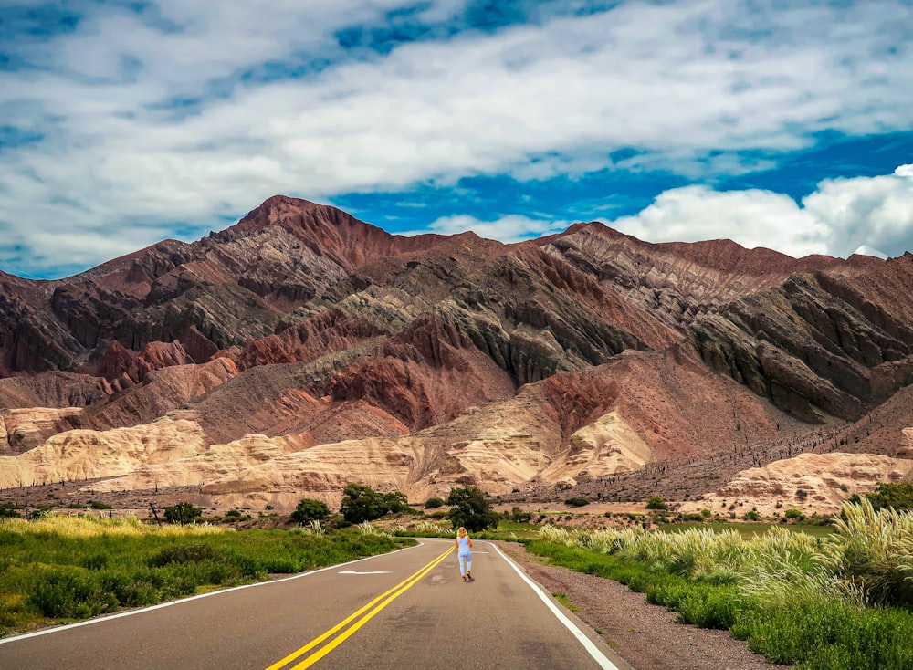 gray asphalt road in between brown mountains under blue sky during daytime