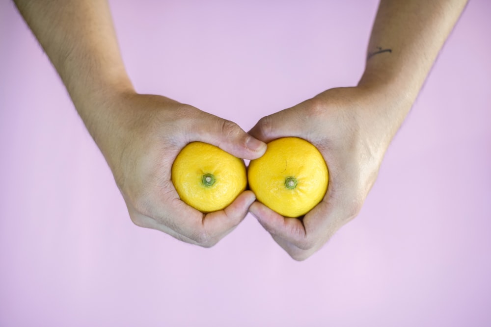 person holding 3 yellow citrus fruits