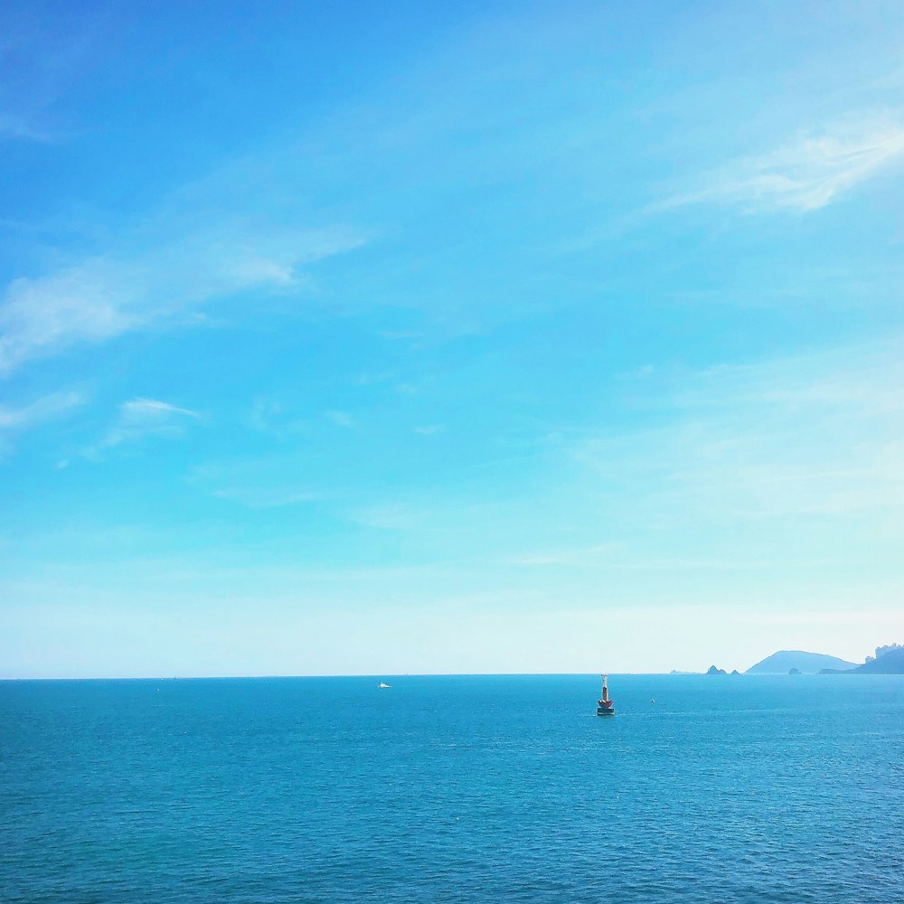 Persona con camisa negra de pie en el mar azul bajo el cielo azul durante el día